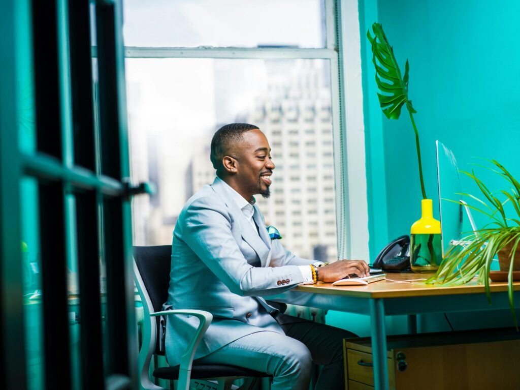 pexels-photo-2422278-2422278 Confident businessman in modern office working on laptop with city view.